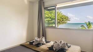 A hotel room with a bed, a view of the ocean, and a window with curtains. - 972L1 - T4 "Taïno" facing the sea (Le Vauclin)