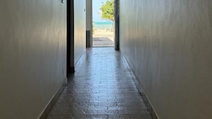 A hallway with a tiled floor leading to a door with a view of the beach. - 972L1 - T4 "Taïno" facing the sea (Le Vauclin)