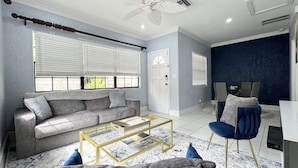 Un salon moderne avec un canapé gris, une table basse et un fauteuil bleu.