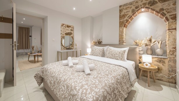 A modern bedroom with a large bed, a stone wall arch, and a mirror. - DP Homes Exarcheia 1Α - Central Stone Apt near Metro & Museum (Athina)