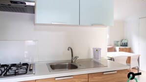 A modern kitchen with a stainless steel sink, a gas stove, and light-colored cabinets. - Hotiday Lago di Levico (Levico Terme)