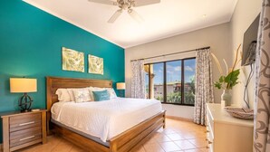 Quarto com cama de madeira, paredes verde-água e uma grande janela com cortinas.