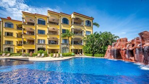 Um hotel com uma grande piscina, várias varandas e uma cascata.