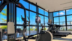Een sportschool met trainingsapparatuur, grote ramen en uitzicht over de stad.