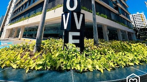 Een modern meerlaags gebouw met een opvallend 'MOVE' bord, omringd door groen en een helderblauwe lucht.