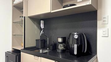 A kitchenette with a coffee maker, a kettle, and a small trash bin.