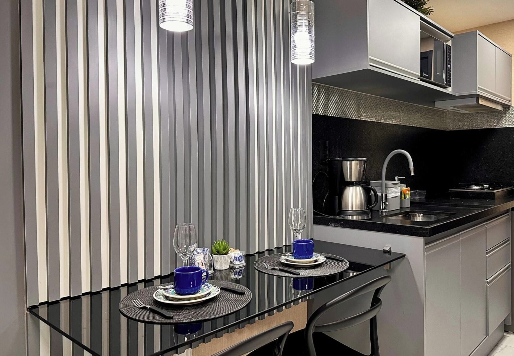 A modern kitchen with a black countertop, stainless steel appliances, and a striped wall.