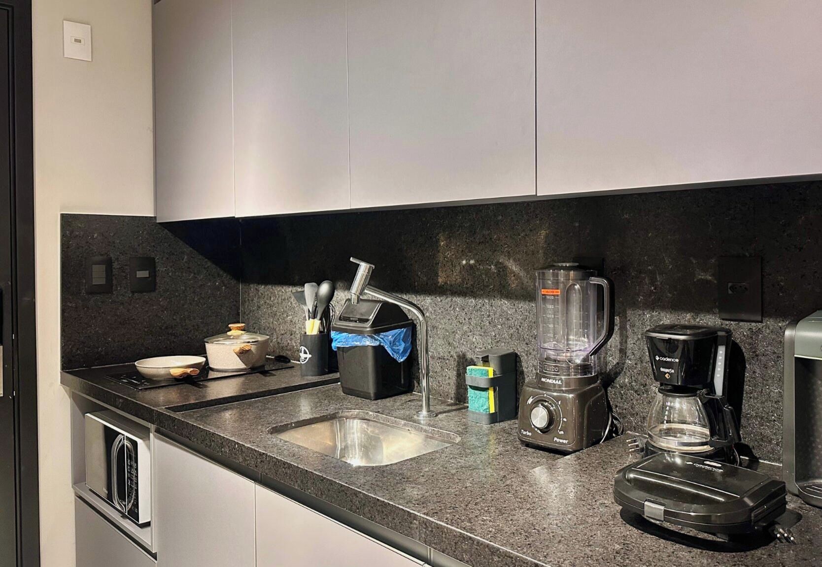 A kitchen with a sink, a blender, a coffee maker, and a toaster.
