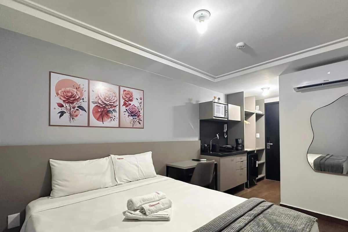Una habitación de hotel con cama, escritorio, kitchenette y baño.