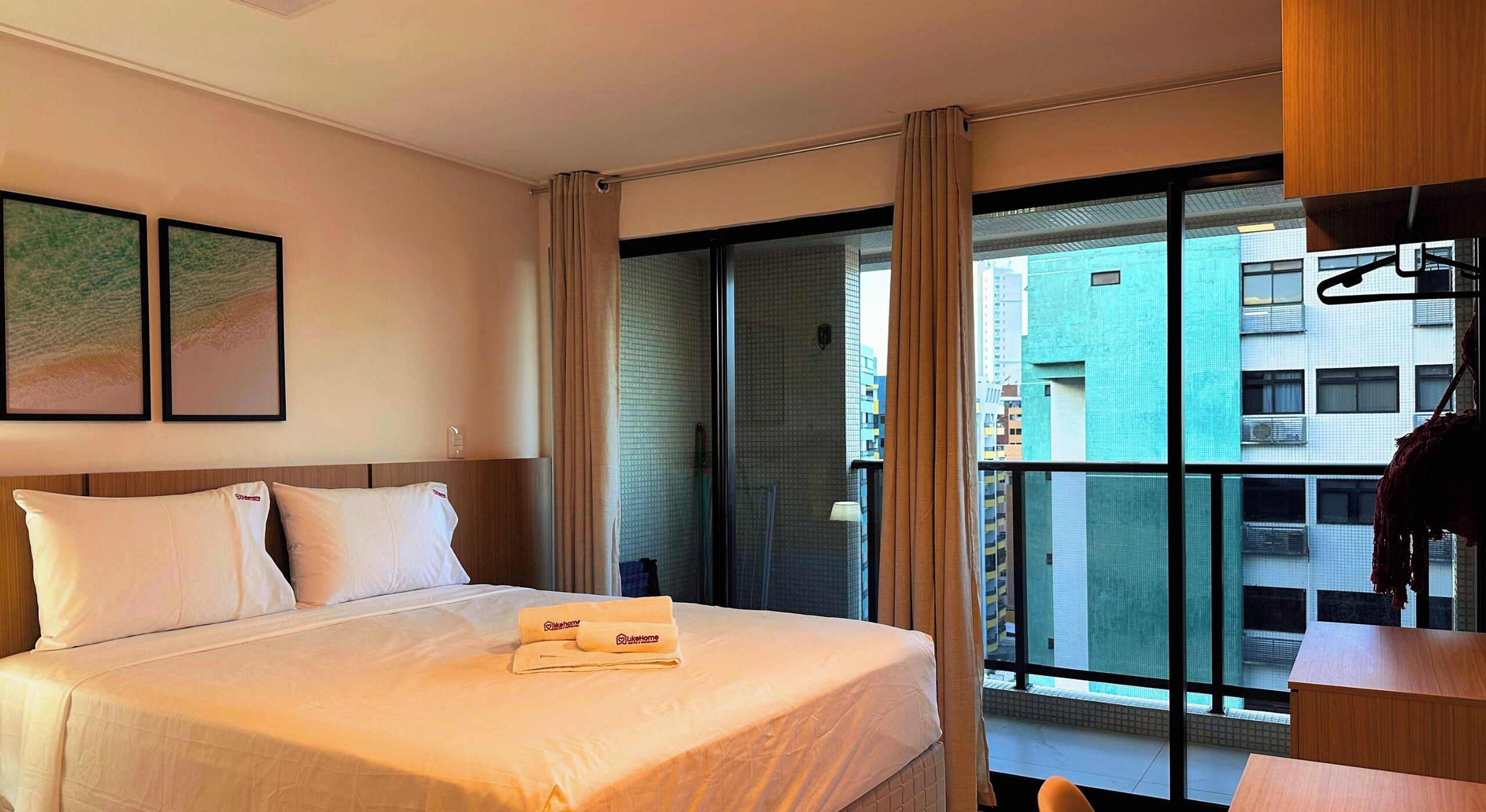 Una habitación de hotel con una cama, un escritorio y vista a la ciudad.