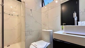 Un baño moderno con inodoro, lavamanos y zona de ducha.