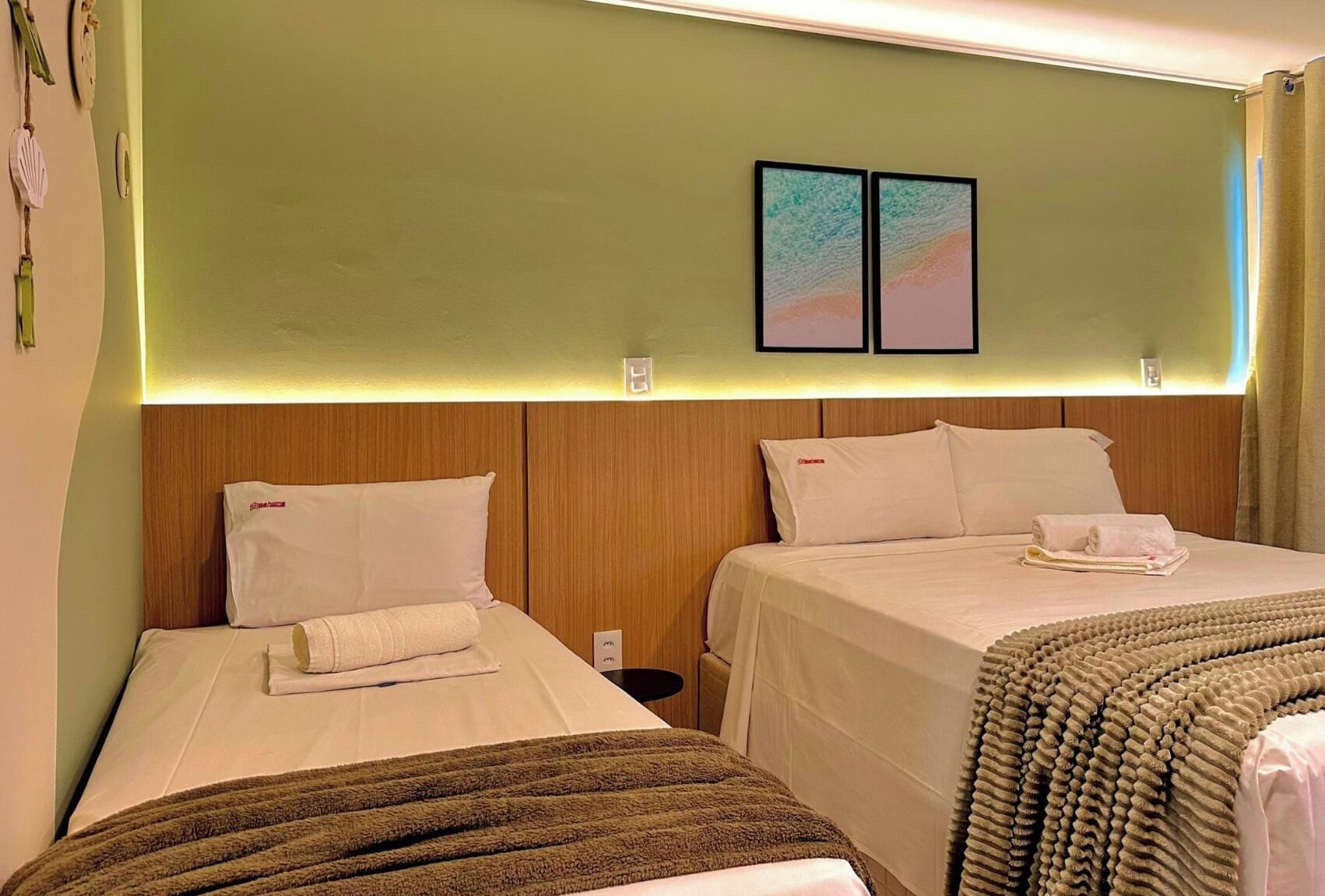 A hotel room with two beds, a wooden headboard, a wall-mounted artwork, and a small bedside table.