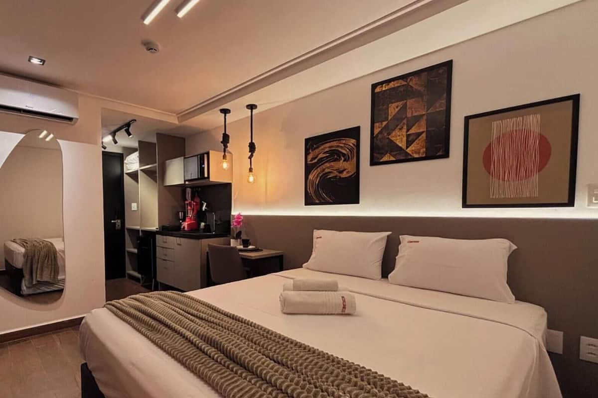 Una habitación de hotel moderna con cama, escritorio y kitchenette.