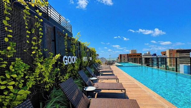 Un área de piscina en la azotea con sillones de descanso y barandilla de cristal.
