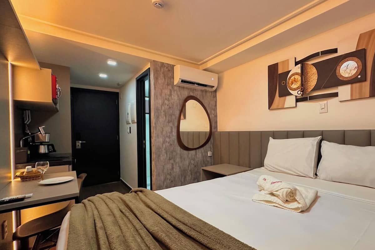 Una habitación de hotel con cama, mesita de noche y espejo.