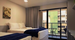 Une chambre d’hôtel avec deux lits, une grande fenêtre et une vue sur le paysage urbain.