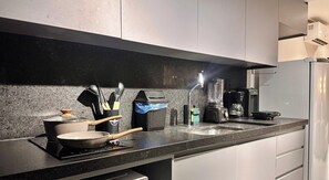 Een moderne keuken met een granieten aanrecht, een kookplaat, een koffiezetapparaat en een blender.