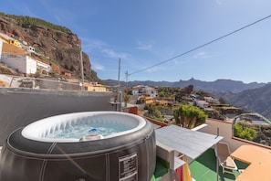 A hot tub on a rooftop with a view of a hillside village.
