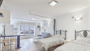 Quarto com duas camas, uma mesinha e um sofá.