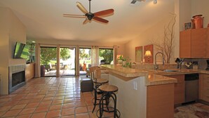 A spacious kitchen with a central island, a ceiling fan, and a large window overlooking a garden. - 2 Bedroom at Woodhaven Country Club in Palm Desert. (Palm Desert)
