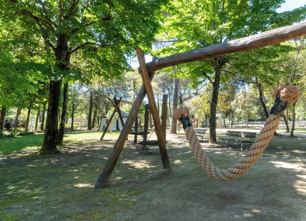 A park with a rope swing, wooden structures, and trees. - Hotiday Lodge Viareggio (Viareggio)