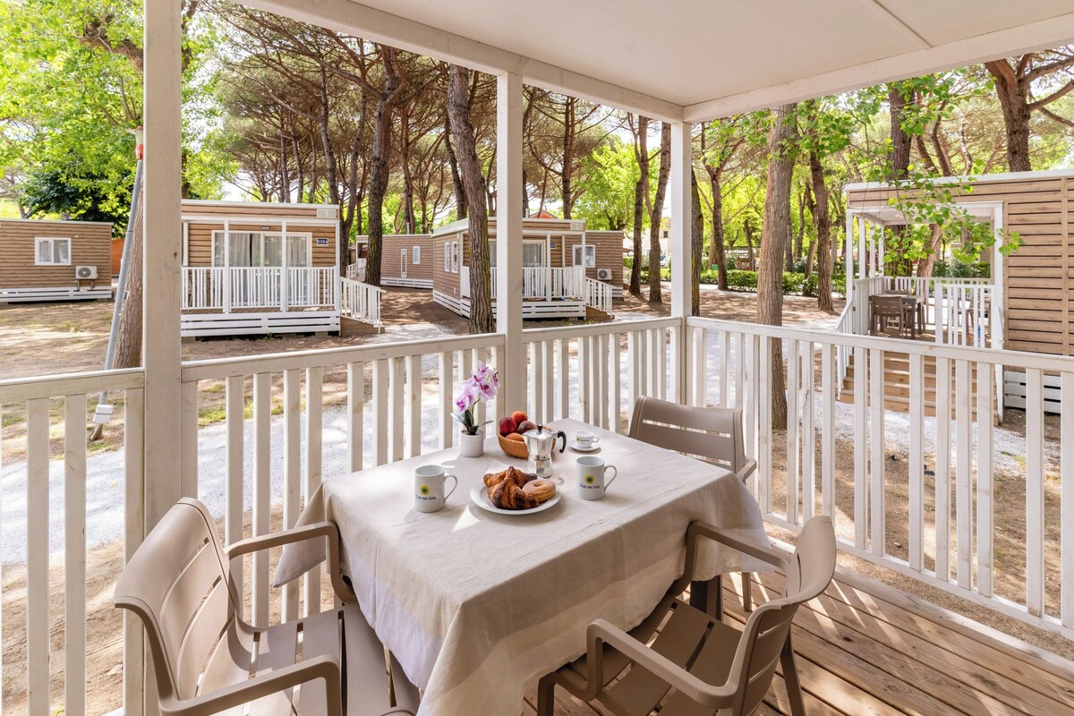 A covered outdoor seating area with a table set for two, surrounded by white railings.