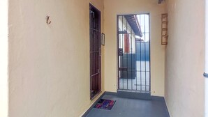 A narrow corridor with a tiled floor, a metal gate, and a small mat. - Cozy house in Balneário Jussara, Mongaguá. Just 600m from the beach. Pets allowed. (Mongaguá)
