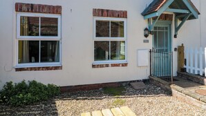 A building with two windows, a small porch, and a white picket fence. - Farriers Cottage (Bridlington)