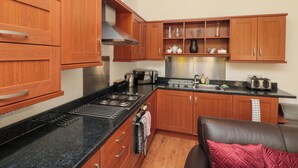 A kitchen with wooden cabinets, a stove, and a countertop. - Farriers Cottage (Bridlington)
