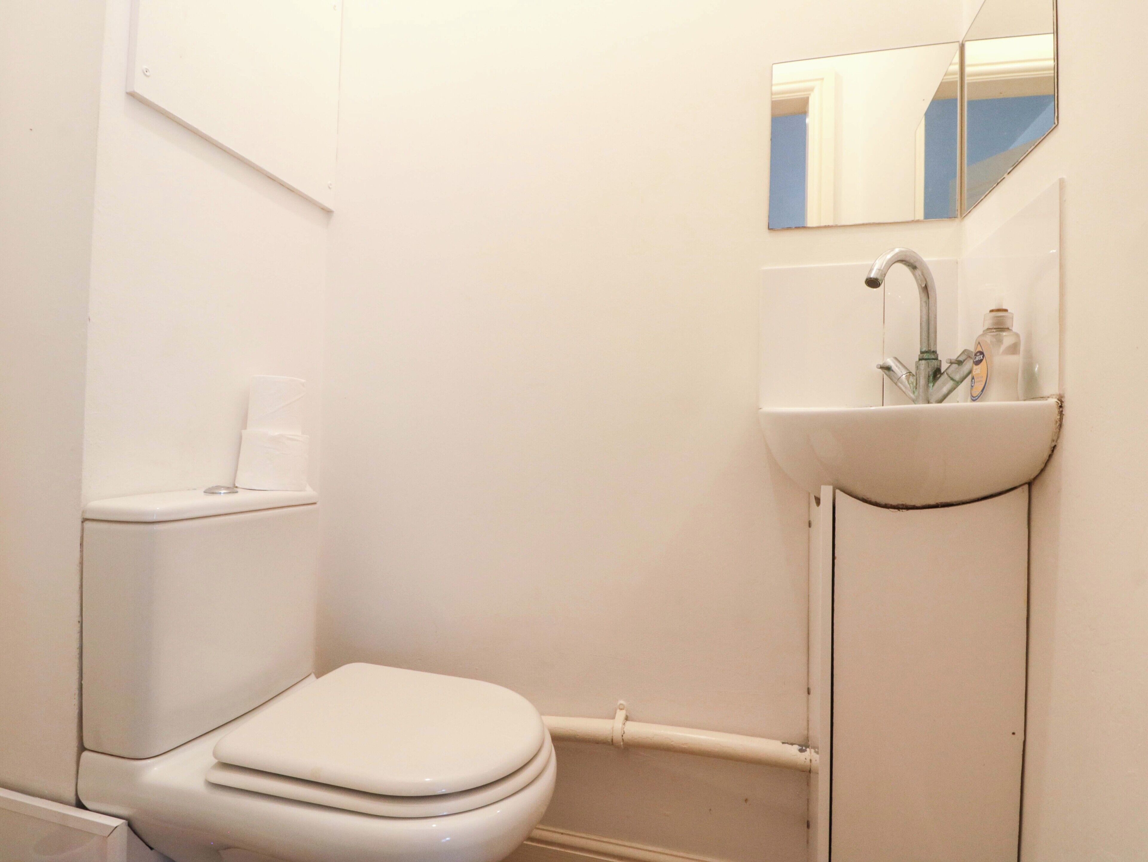Un baño pequeño y blanco con inodoro, lavamanos y espejo.