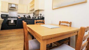 A compact kitchen with modern appliances, a dining table with chairs, and a large mirror on the wall. - Chestnut Cottage (Bridlington)