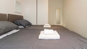 A bedroom with two beds, a mirror, and a door. - Chestnut Cottage (Bridlington)