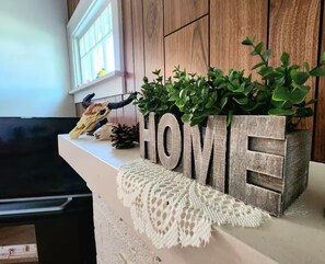 A wooden block with the word "HOME" and a plant on top, placed on a white surface with a woven item underneath. - The Cozy Corner in central Casper (Casper)