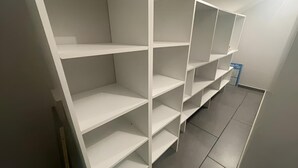 A room with white shelving units and a tiled floor.