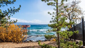 A beach with a wooden viewing platform, sandy shore, and ocean waves. - Relaxed Lakefront Living • Cozy 1BR Tahoe Condo (Tahoe Vista)