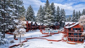 Une station de ski recouverte de neige, avec plusieurs bâtiments rouges, une piscine et des arbres environnants.