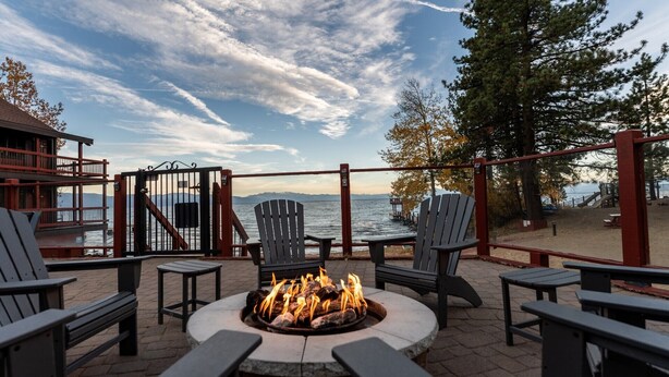 An outdoor seating area with Adirondack chairs, a fire pit, and a view of the water and mountains. - 2BR Tahoe Snowfall, Lake Mist & Crackling Fires (Tahoe Vista)