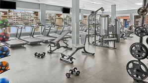 Ein Fitnessstudio mit Laufbändern, Krafttrainingsgeräten und Kurzhanteln.
