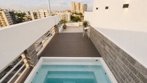 Una piscina en la azotea con terraza de madera y vistas a la ciudad.