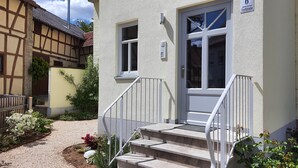 A two-story building with a traditional half-timbered facade and a modern entrance. - Fewo am Kirchbrunnen (DG) - Quiet time out for 2 (Urspringen vor der Rhön)