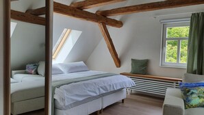 A bedroom with a sloped ceiling, a bed, a bench, a window, and a radiator. - Fewo am Kirchbrunnen (DG) - Quiet time out for 2 (Urspringen vor der Rhön)