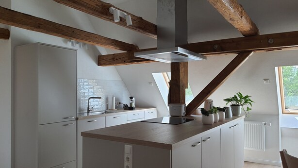 A modern kitchen with white cabinetry, a wooden ceiling, and a window providing natural light. - Fewo am Kirchbrunnen (DG) - Quiet time out for 2 (Urspringen vor der Rhön)