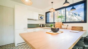 A modern kitchen with white cabinets, a wooden island, and pendant lighting. - Belle maison moderne proche plages & bourg (Carnac)