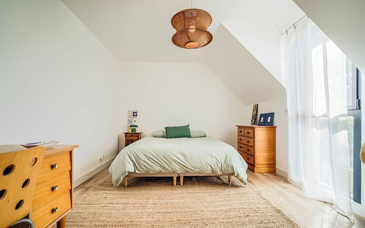 Ein Schlafzimmer mit einem Bett, einem Holzschrank und einer Pendelleuchte.