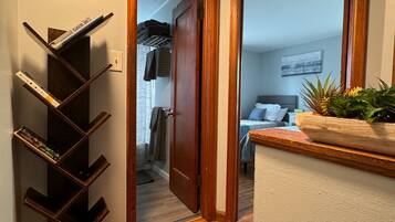 Un couloir avec un plancher en bois, une bibliothèque remplie de livres et une porte qui donne sur une chambre à coucher.