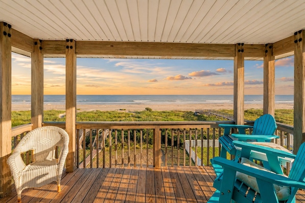 A wooden deck with a view of the beach, two chairs, and a railing. - Beachfront | 4BR | Wide Decks | Sleeps 14 (Galveston)