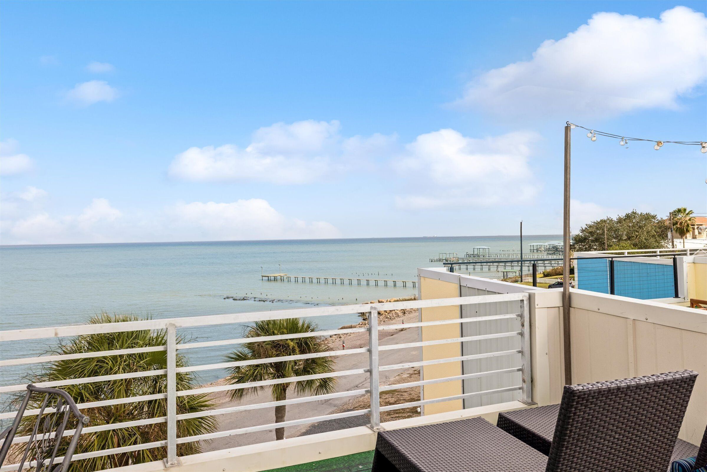 Un balcón con vista al mar, una palmera y una silla.
