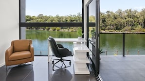 Een modern kantoor met een bureau, twee stoelen en uitzicht op een meer en bomen.