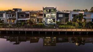 Een moderne woonwijk met meerhooghuizen, een steiger en een rustig waterlichaam dat de gebouwen weerspiegelt.
