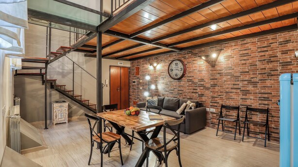 Un intérieur moderne avec une table à manger en bois, des chaises, un canapé et un mur en briques.